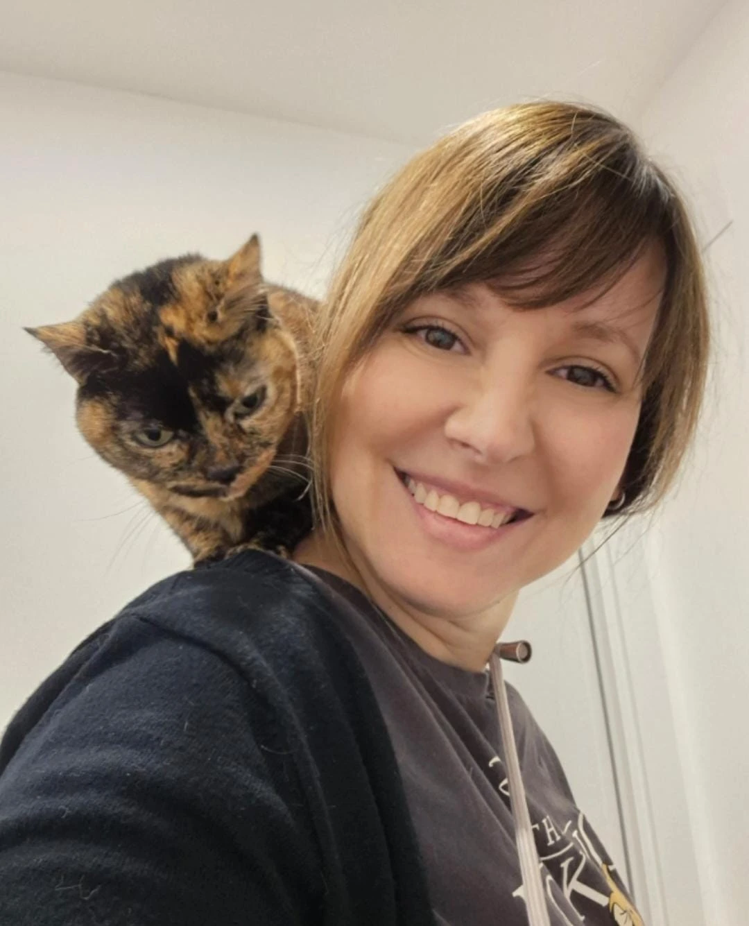 Eva con un gato carey apoyado en su hombro
